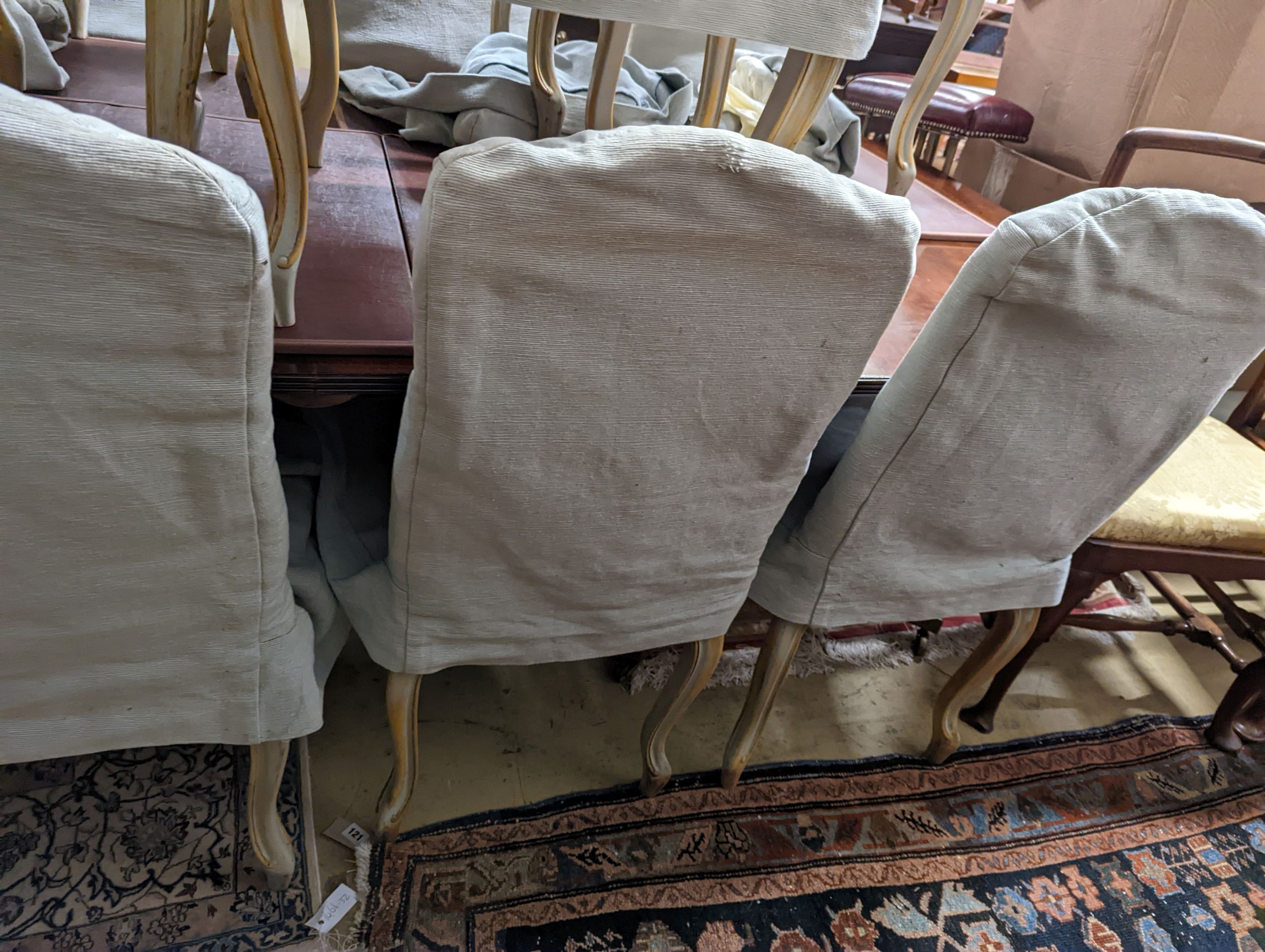 A set of fourteen French Louis XV style painted upholstered dining chairs with loose covers